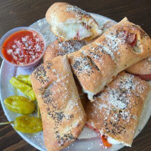 Pepperoni rolls with a side of marinara sauce and peppers. 